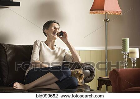 Senior woman sitting on sofa talking on telephone View Large Photo Image Stock Image - Senior woman sitting on sofa talking on telephone. Fotosearch
