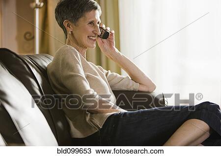 Senior woman sitting on sofa talking on telephone View Large Photo Image Stock Image - Senior woman sitting on sofa talking on telephone. Fotosearch