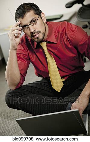 Stock Photo - Serious businessman sitting on floor using laptop. Fotosearch