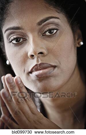 Stock Image - Serious woman with hands clasped. Fotosearch