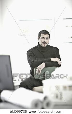 Stock Photograph - Smiling businessman sitting architect's in office. Fotosearch