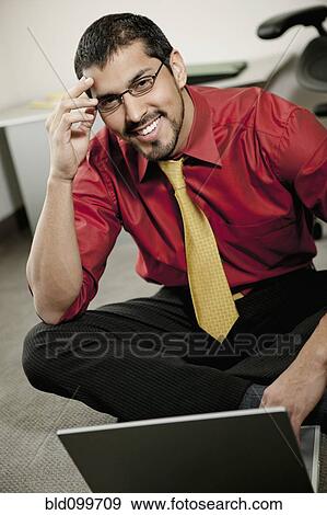 Stock Photo - Smiling businessman sitting on floor using laptop. Fotosearch