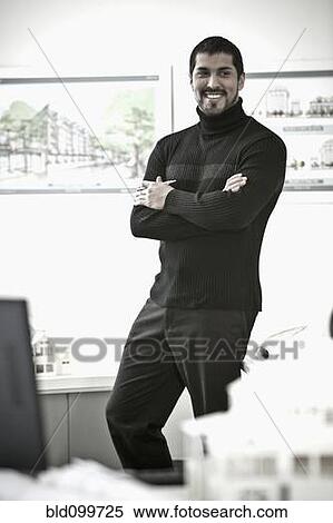 Smiling businessman standing in office View Large Photo Image Stock Photography - Smiling businessman standing in office. Fotosearch
