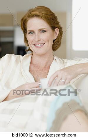 Stock Image - Smiling Caucasian woman drinking coffee. Fotosearch