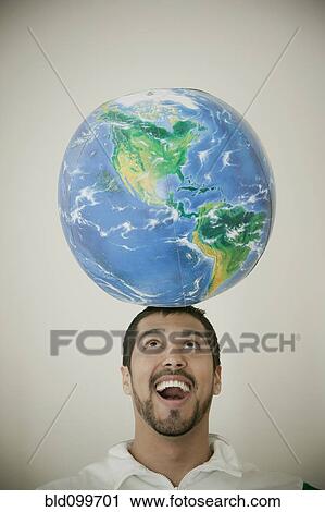 Stock Image - Smiling man balancing globe in his head. Fotosearch