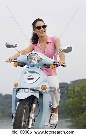 Stock Photography - Smiling woman riding on scooter. Fotosearch