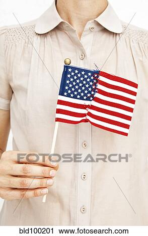 Stock Image - Woman holding repaired American flag. Fotosearch