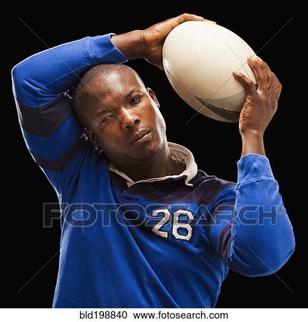 Stock Image - African American athlete holding rugby ball. Fotosearch