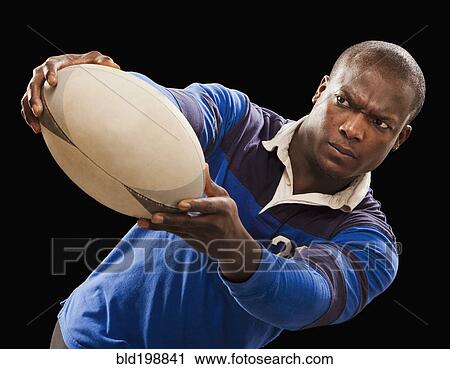 Stock Image - African American athlete holding rugby ball. Fotosearch