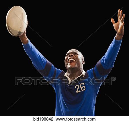 Stock Image - African American athlete holding rugby ball. Fotosearch