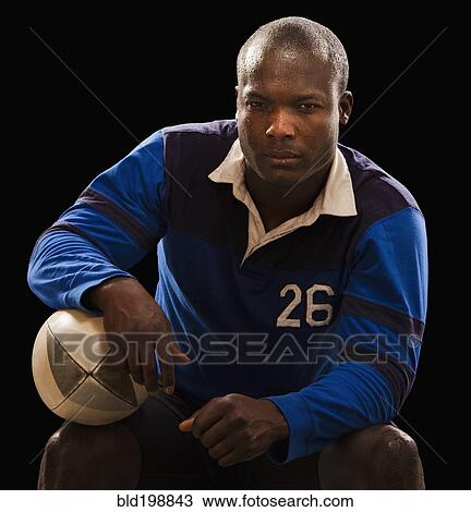 Stock Image - African American athlete holding rugby ball. Fotosearch