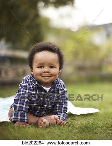 Picture - African American baby sitting in grass. Fotosearch