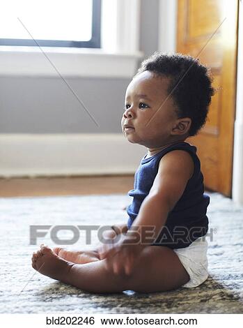 Stock Photograph - African American baby sitting on floor. Fotosearch