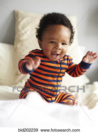 Stock Photo - African American boy sitting on bed. Fotosearch