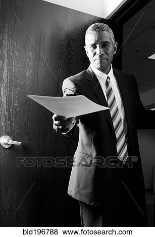 African American businessman holding out paperwork View Large Photo Image Stock Photo - African American businessman holding out paperwork. Fotosearch