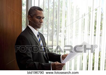 Stock Image - African American businessman looking at paperwork. Fotosearch