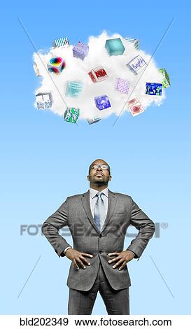 Stock Photo - African American businessman looking at cloud containing cubes with pictures. Fotosearch