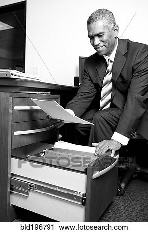 African American businessman putting paperwork in drawer View Large Photo Image Stock Image - African American businessman putting paperwork in drawer. Fotosearch