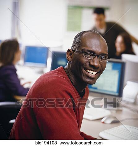 Stock Photo - African American businessman sitting at desk. Fotosearch