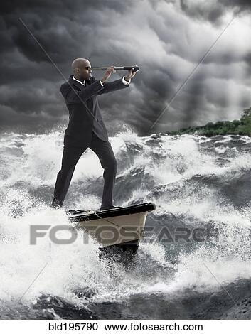 Stock Image - African American businessman using telescope on boat. Fotosearch