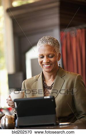 Stock Image - African American businesswoman using digital tablet in cafe. Fotosearch