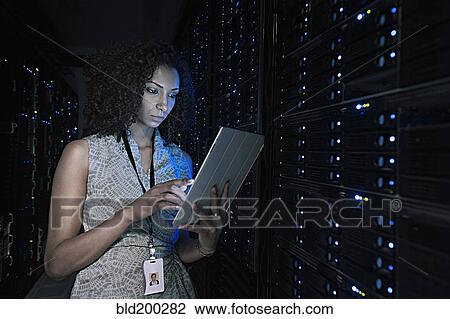 Stock Image - African American businesswoman working in server room. Fotosearch