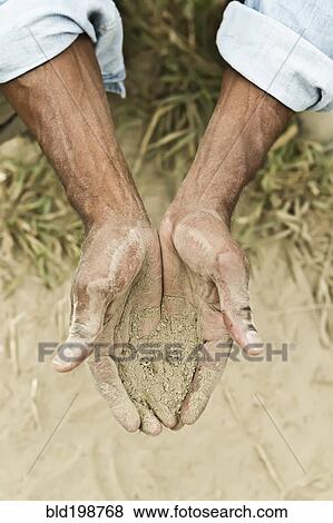 Stock Photo - African American farmer checking dirt in field. Fotosearch