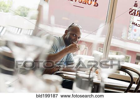 Stock Photo - African American man drinking coffee in restaurant. Fotosearch