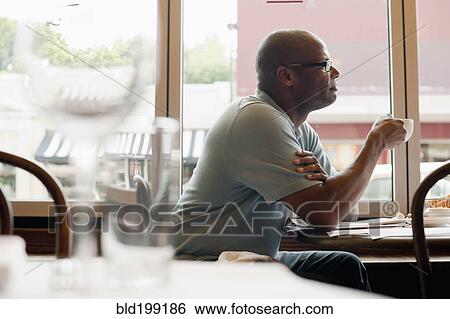 Stock Photograph - African American man drinking coffee in restaurant. Fotosearch