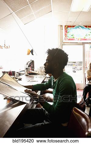 Stock Image - African American man reading menu at diner counter. Fotosearch