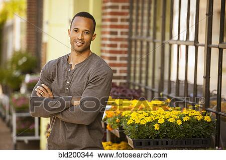 Picture - African American man standing near flower shop. Fotosearch