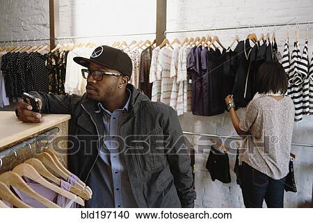 African American man text messaging on cell phone in clothing store View Large Photo Image Stock Image - African American man text messaging on cell phone in clothing store. Fotosearch