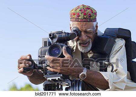 Stock Image - African American man using film camera. Fotosearch