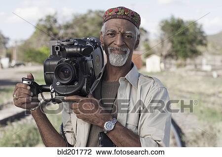Stock Image - African American man using film camera. Fotosearch