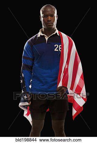 Picture - African American rugby player wrapped in American flag. Fotosearch
