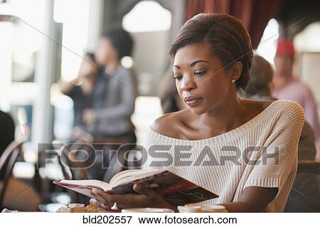 Stock Photo - African American woman reading book in cafe. Fotosearch