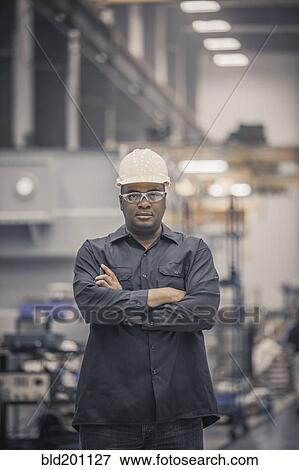 Stock Photo - African American worker standing in factory. Fotosearch