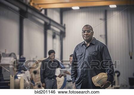 Stock Photograph - African American worker standing in factory. Fotosearch