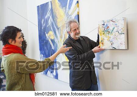 Art gallery curator hanging painting on wall View Large Photo Image Stock Image - Art gallery curator hanging painting on wall. Fotosearch