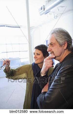 Stock Image - Art gallery curator talking to customer. Fotosearch