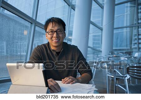 Stock Photography - Asian businessman working with digital tablet in cafe. Fotosearch