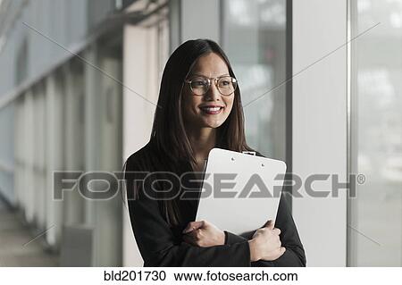 Stock Image - Asian businesswoman holding clipboard. Fotosearch