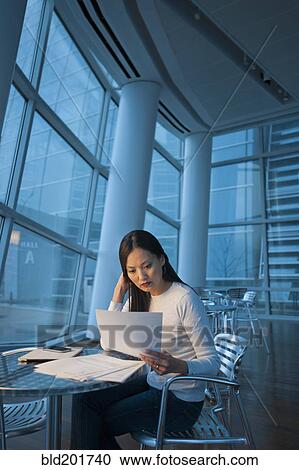 Stock Image - Asian businesswoman looking at paperwork. Fotosearch