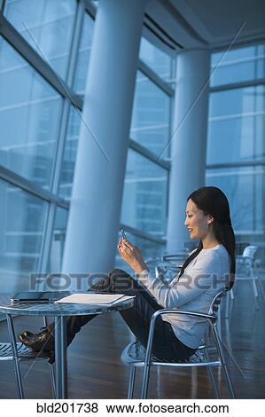 Asian businesswoman text messaging on cell phone View Large Photo Image Stock Photo - Asian businesswoman text messaging on cell phone. Fotosearch