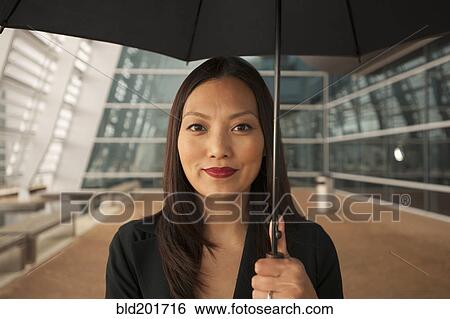 Stock Photograph - Asian businesswoman underneath umbrella. Fotosearch
