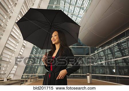 Stock Photography - Asian businesswoman underneath umbrella. Fotosearch