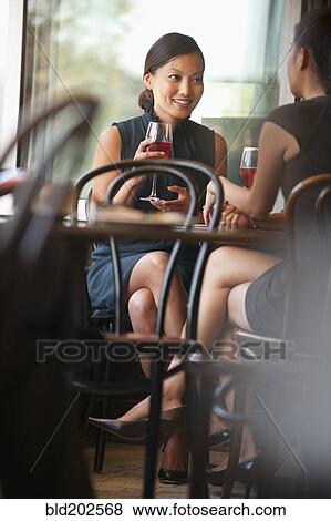 Stock Photo - Asian friends drinking wine in cafe. Fotosearch