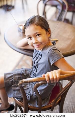 Picture - Asian girl sitting in cafe. Fotosearch