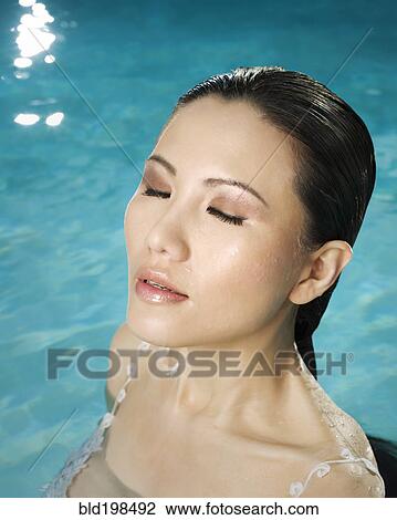 Asian woman in swimming pool with eyes closed View Large Photo Image Stock Image - Asian woman in swimming pool with eyes closed. Fotosearch