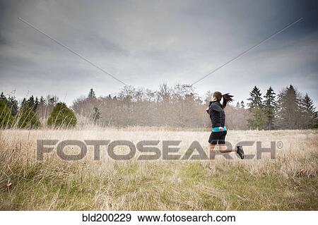 Stock Photo - Asian woman jogging in field. Fotosearch